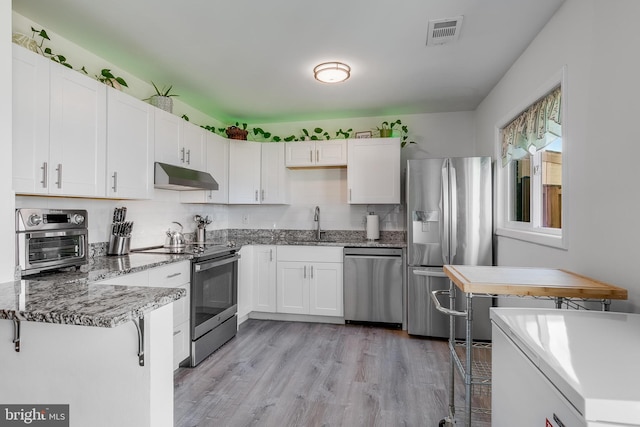 kitchen with white cabinets, under cabinet range hood, visible vents, and stainless steel appliances