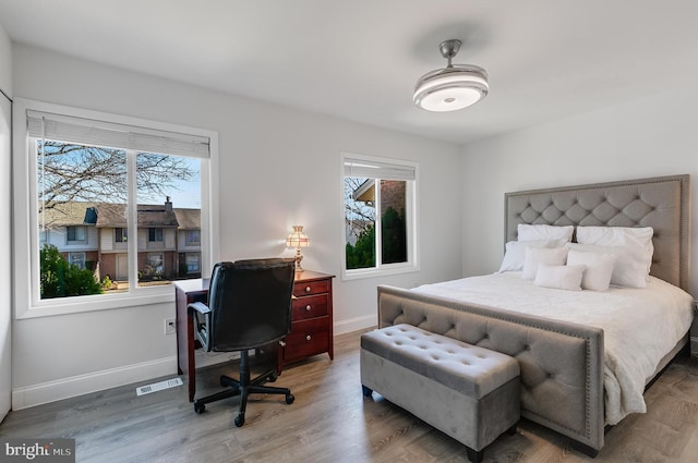 bedroom featuring visible vents, baseboards, and wood finished floors