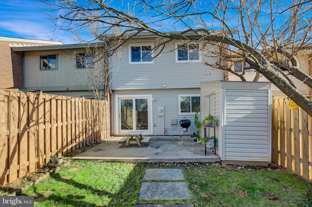 rear view of property with a fenced backyard and a patio