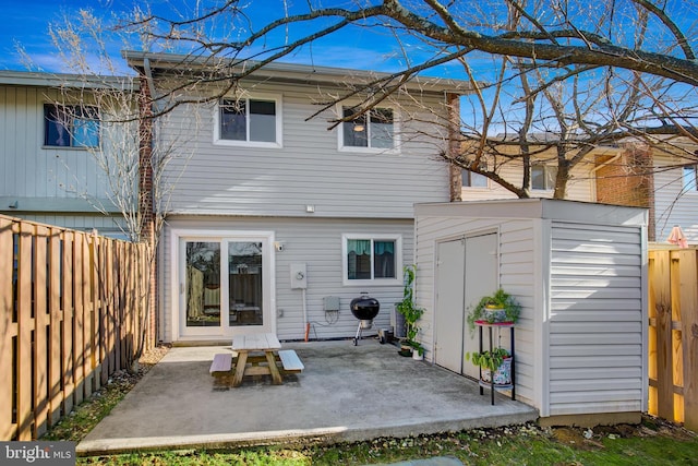 rear view of property featuring an outbuilding, a storage unit, a patio area, and a fenced backyard