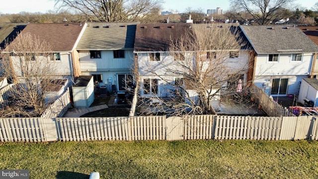 rear view of house featuring a fenced backyard and a yard