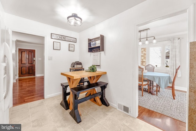 dining area featuring light wood-style floors, baseboards, visible vents, and crown molding