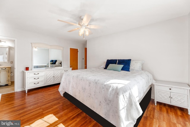 bedroom featuring ensuite bathroom, wood finished floors, and a ceiling fan