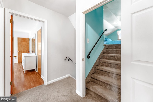 stairway featuring lofted ceiling, carpet flooring, and baseboards