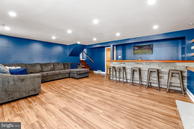 living area featuring stairs, indoor wet bar, wood finished floors, and recessed lighting