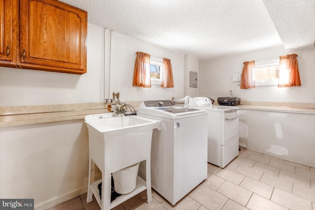 washroom featuring a textured ceiling, separate washer and dryer, cabinet space, and a healthy amount of sunlight