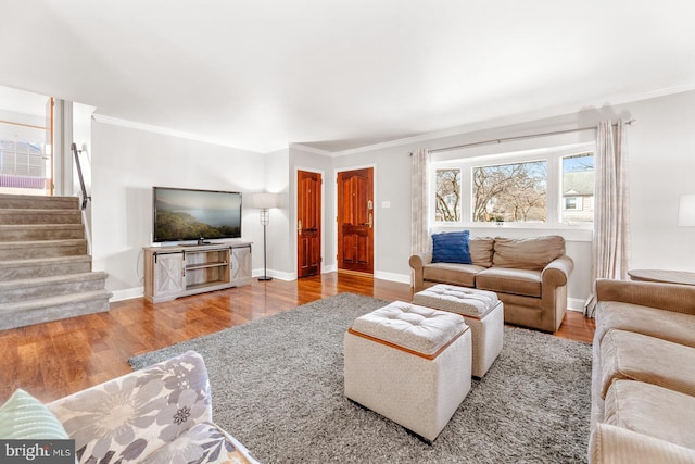 living area with wood finished floors, crown molding, baseboards, and stairs