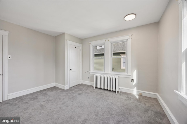 spare room featuring carpet floors, baseboards, and radiator heating unit