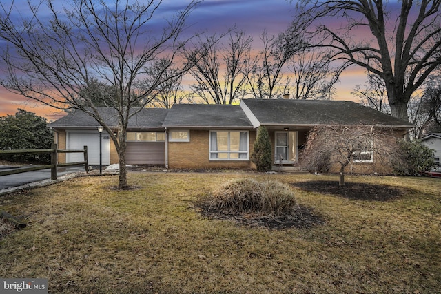 ranch-style home with a garage, a yard, brick siding, and driveway