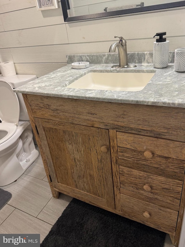 half bath featuring toilet, wood walls, and vanity