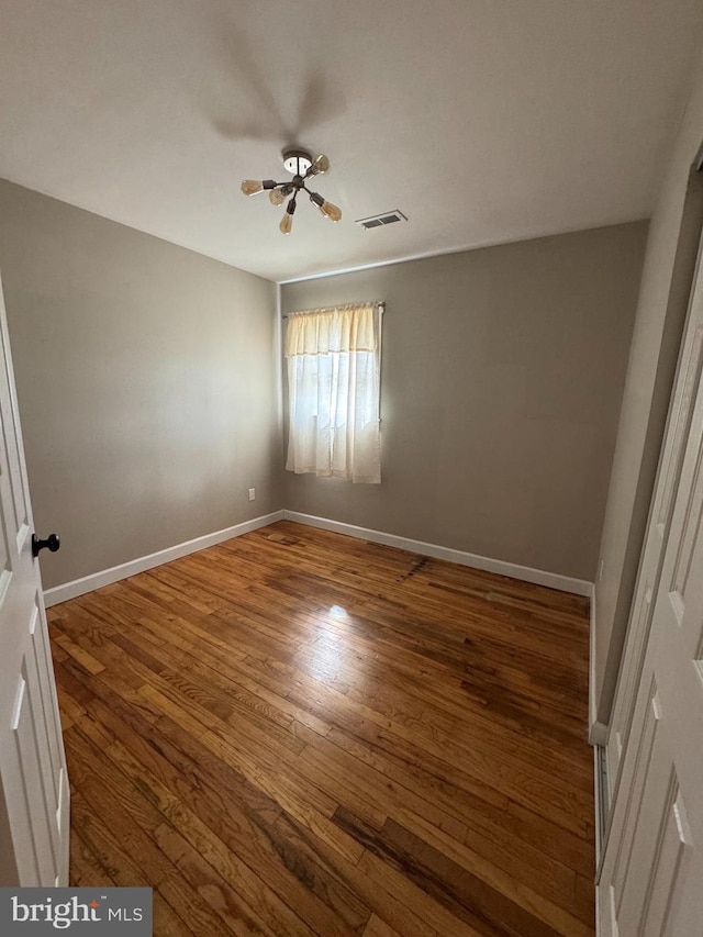 unfurnished bedroom with baseboards, visible vents, and wood finished floors