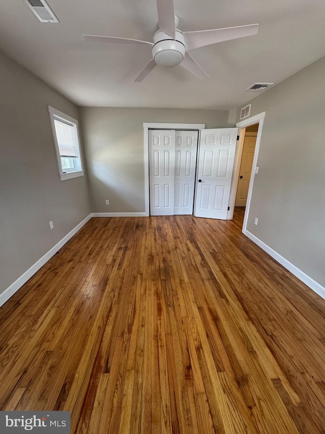 unfurnished bedroom with visible vents, baseboards, and hardwood / wood-style flooring