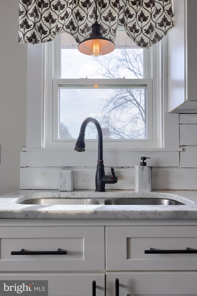 details with light stone countertops, white cabinetry, and a sink