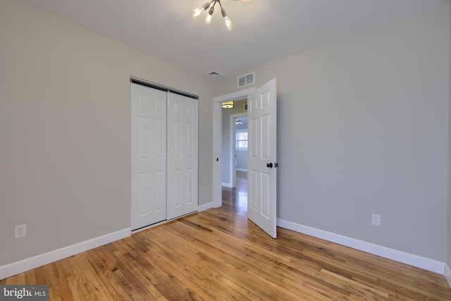 unfurnished bedroom with visible vents, a closet, light wood-style flooring, and baseboards