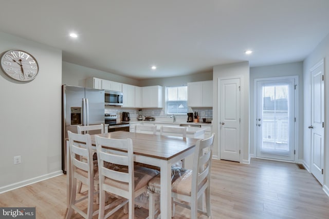 dining space featuring light wood finished floors, baseboards, and recessed lighting