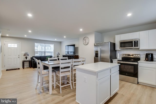 kitchen featuring a center island, light wood finished floors, stainless steel appliances, decorative backsplash, and open floor plan