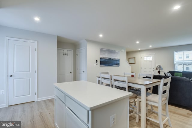 kitchen with light wood finished floors, recessed lighting, light countertops, open floor plan, and a kitchen island