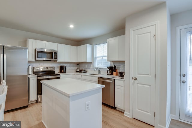 kitchen with light wood-style floors, appliances with stainless steel finishes, white cabinets, and a sink