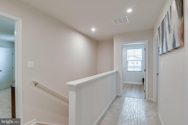 corridor featuring recessed lighting, light carpet, visible vents, baseboards, and an upstairs landing