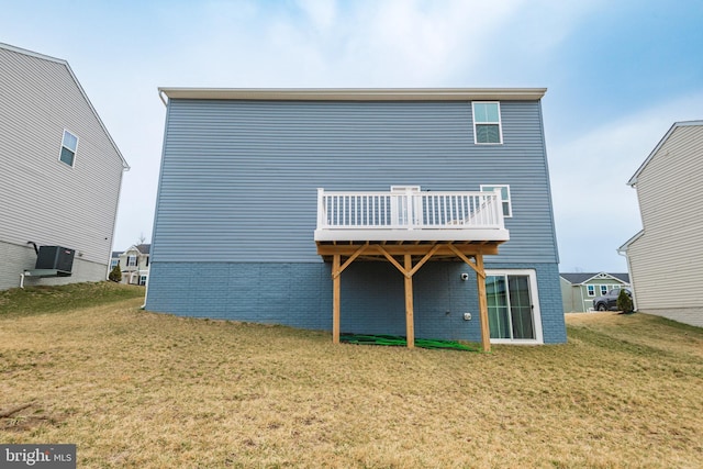 back of property with a deck, a lawn, and brick siding