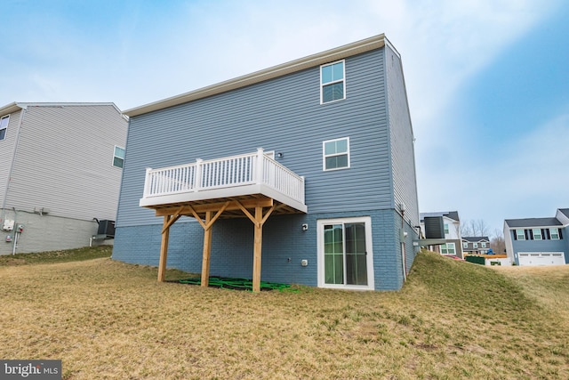 rear view of property featuring brick siding, a lawn, and a deck