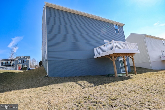 rear view of property with a deck, brick siding, and a lawn