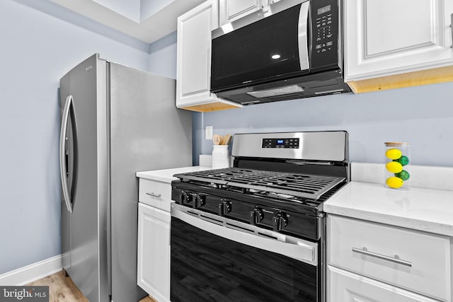 kitchen featuring white cabinets, light stone countertops, baseboards, and stainless steel appliances