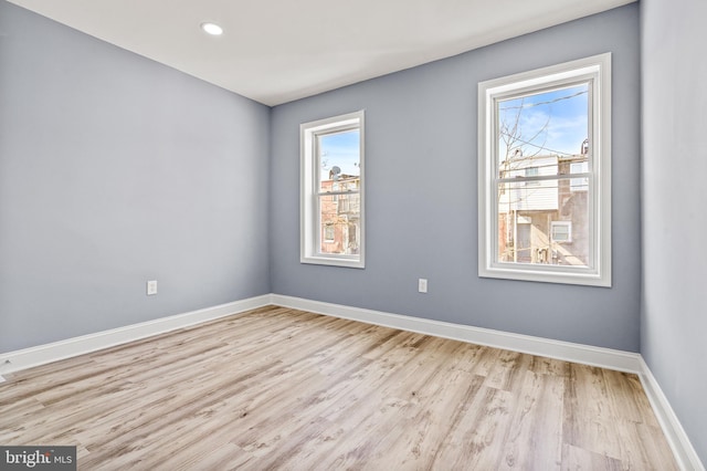 spare room featuring light wood-style floors, baseboards, a wealth of natural light, and recessed lighting