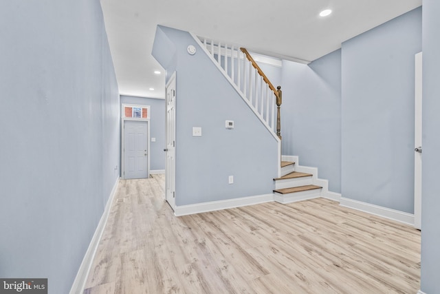 interior space featuring light wood-style floors, baseboards, and stairs