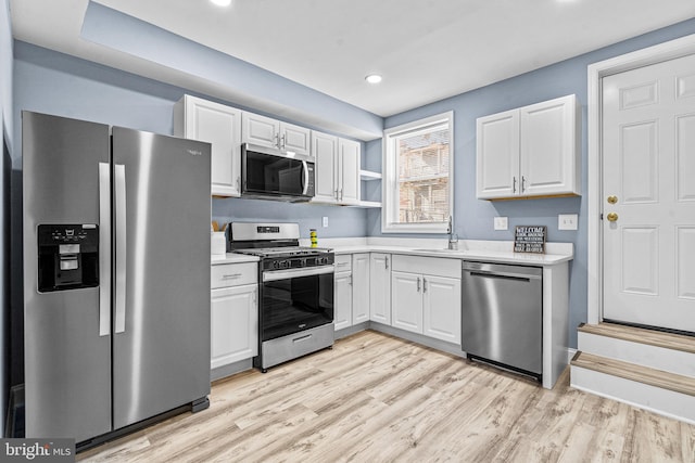 kitchen featuring white cabinets, light wood finished floors, stainless steel appliances, and light countertops