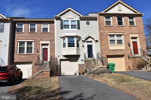 townhome / multi-family property with driveway, brick siding, and an attached garage