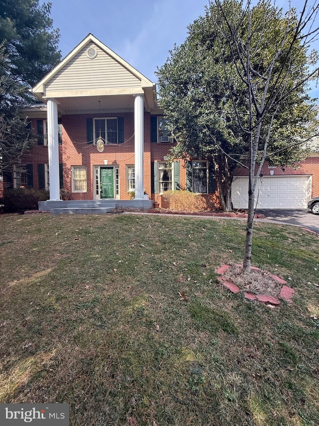 greek revival inspired property with a front lawn, a garage, and brick siding