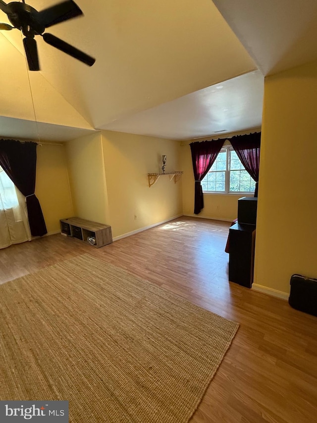 unfurnished living room featuring baseboards, wood finished floors, ceiling fan, and vaulted ceiling