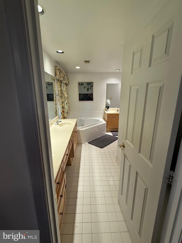 bathroom with a garden tub, visible vents, two vanities, a sink, and tile patterned floors