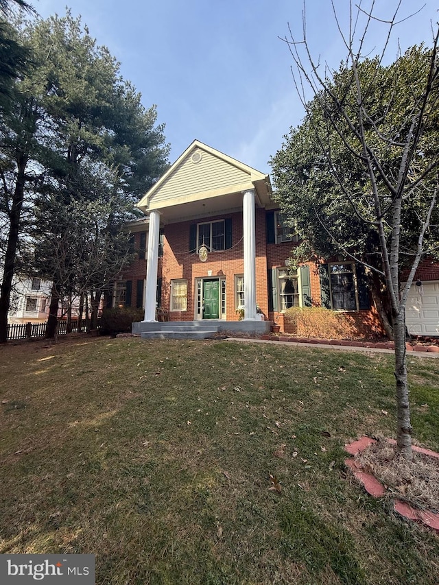 greek revival inspired property featuring brick siding and a front yard