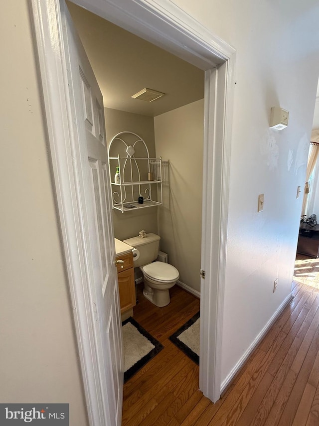 bathroom featuring visible vents, toilet, wood finished floors, and baseboards