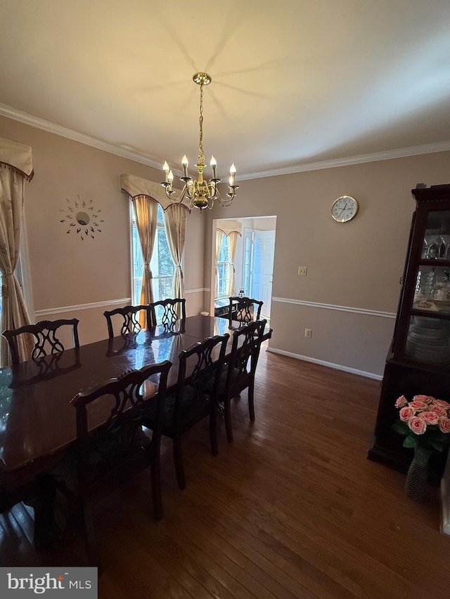 dining space featuring dark wood finished floors, crown molding, baseboards, and an inviting chandelier