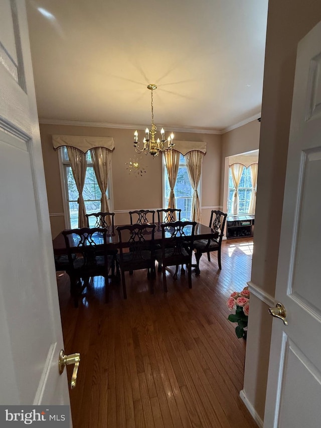 dining area featuring dark wood finished floors, an inviting chandelier, and ornamental molding