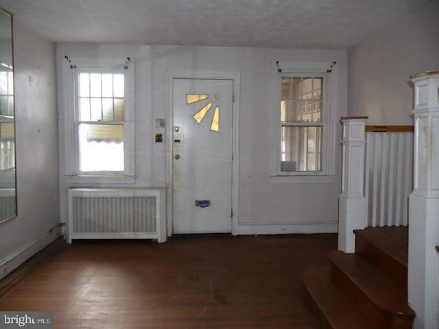 foyer entrance featuring stairway, dark wood finished floors, and radiator