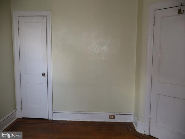 spare room with dark wood-style flooring and baseboards