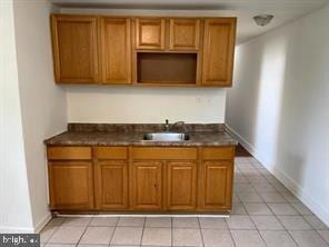 kitchen featuring dark countertops, brown cabinetry, and a sink