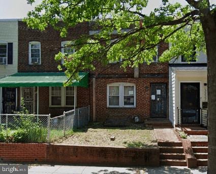 view of front of home with brick siding and fence