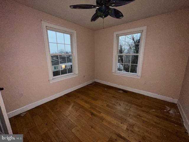 spare room featuring dark wood-style floors, baseboards, and a ceiling fan