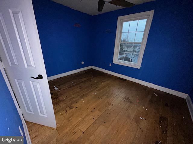 empty room with baseboards, a ceiling fan, and hardwood / wood-style floors