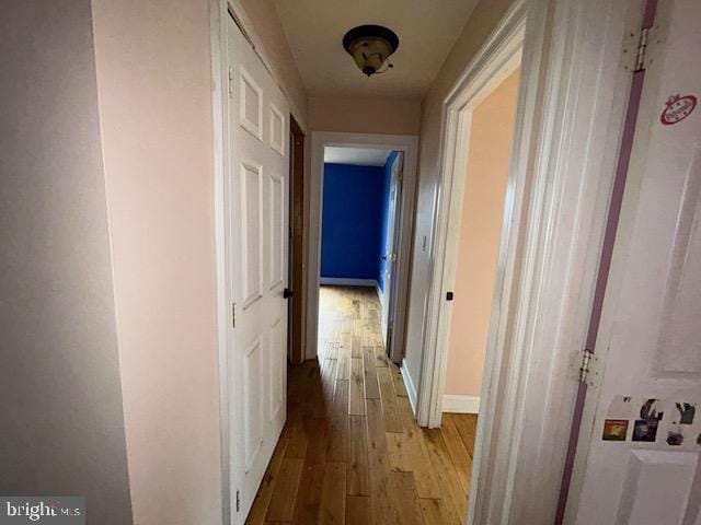 hall featuring light wood-style flooring and baseboards