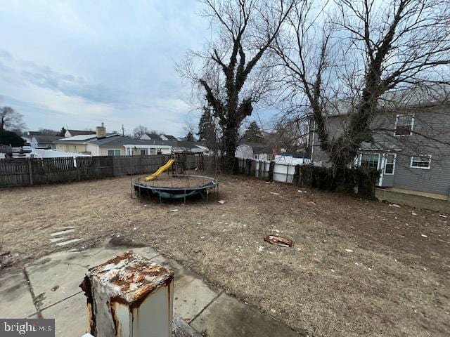 view of yard with a trampoline, a playground, and a fenced backyard