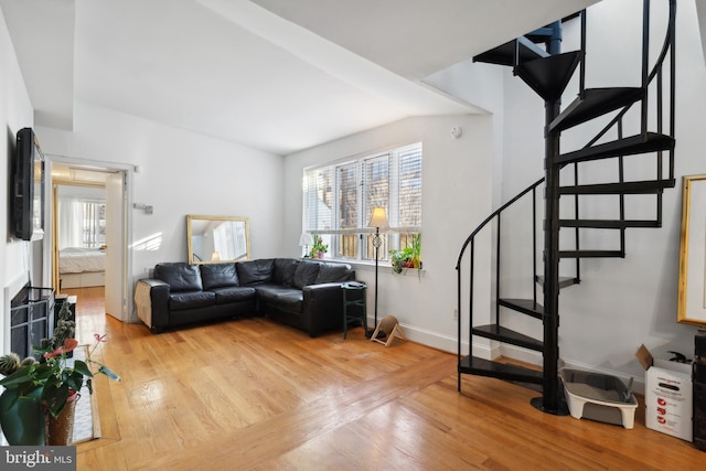 living area featuring stairs, baseboards, and light wood-style floors