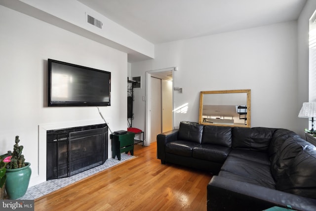 living area with a fireplace, visible vents, and wood finished floors