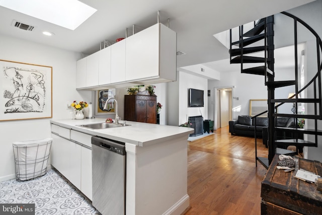 kitchen with a skylight, visible vents, dishwasher, light countertops, and a sink