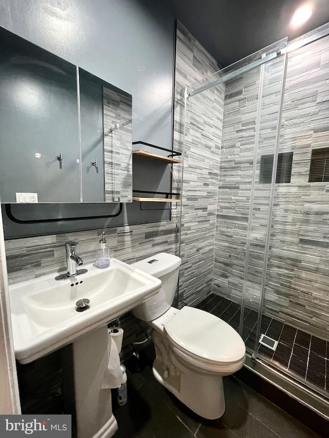 bathroom featuring toilet, a shower stall, tile walls, and tile patterned floors